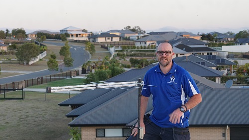 Technician on a roof standing next to an antenna