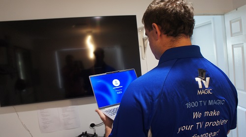 Back of technician, attending to a TV damage report