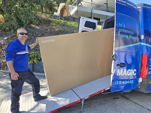 Technician loading a large TV into van