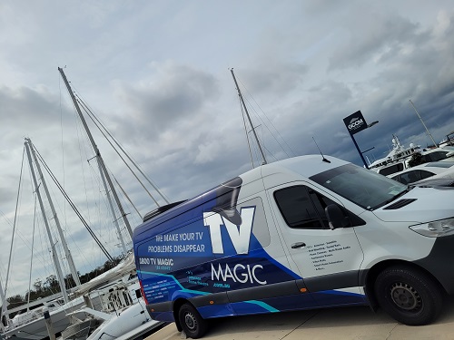 TV Magic van in a marina next to yachts.