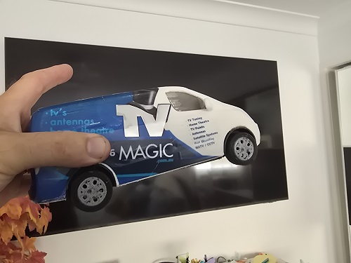 Tiny van held up to a wall mounted TV