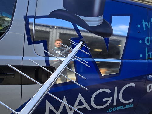 An aerial being held up next to TV Magic van
