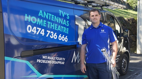 Technician next to van with antenna in hand.