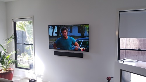 a wall mounted TV with floating sound bar