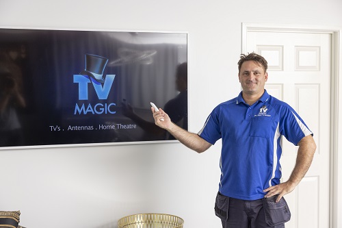 Technician next to a TV, holding a TV remote