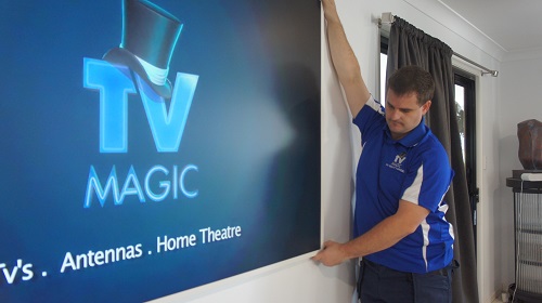 Technician wall mounting a large TV