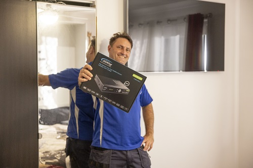 Technician holding up a Vast box in front of a wall mounted TV