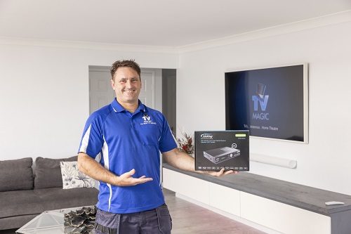 Technician holding a vast box in front of a wall mounted TV