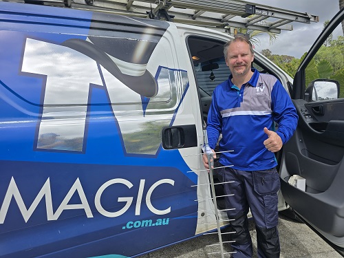 Technician with an antenna, standing next to his van