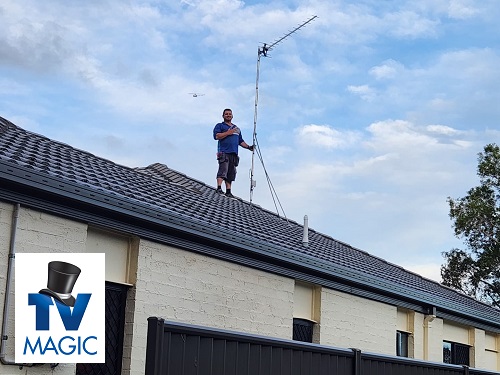 Technician on a roof with an antenna with extended mast