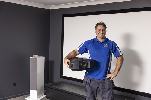 Technician in home theatre, holding a projector
