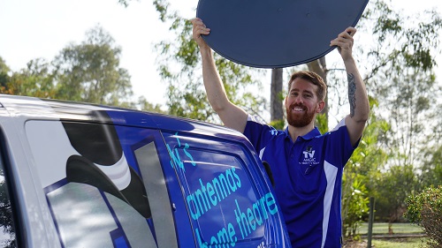 Technician holding a satellite dish above his head.