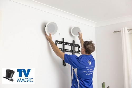 Technician holding speakers up to wall