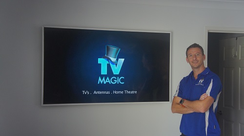 Jim with a  newly installed TV mounted on a wall