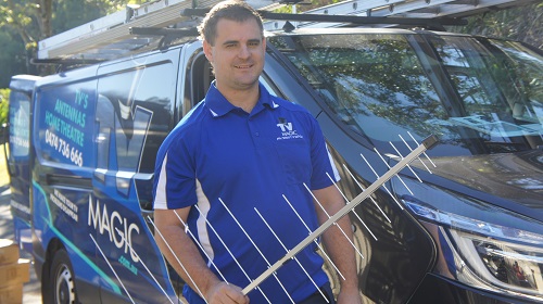 Technician standing next to his van holding an antenna