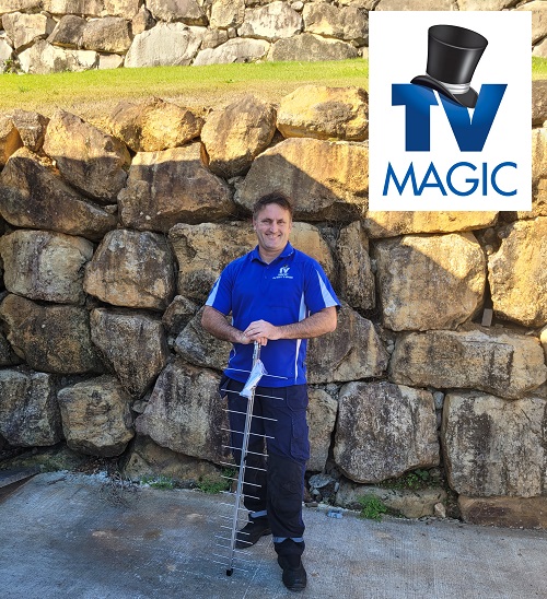 Technician holding an antenna, standing in front of a rock wall