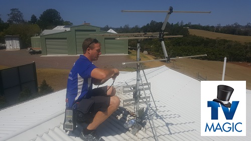Technician on a roof repairing an antenna. Logo in bottom right corner