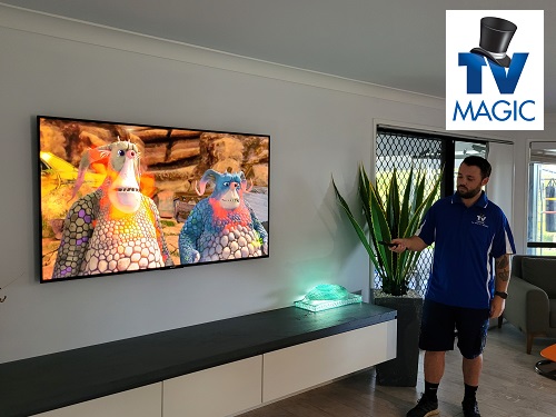 technician in front of a newly installed TV, setting it up.