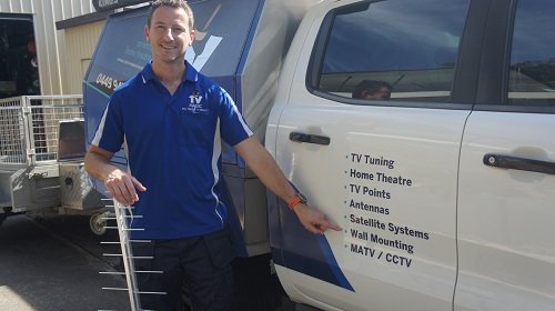 Jim pointing to TV wall mounting signage on the side of his vehicle