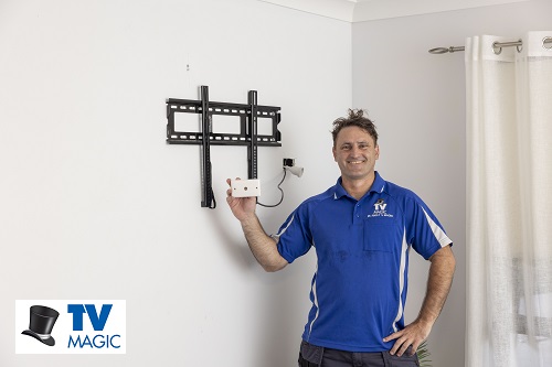 Technician holding up a TV point in front of a wall bracket he installed. Logo in bottom left corner.