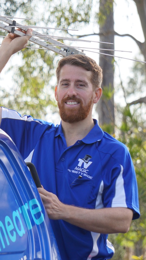 Technician - Gordon, standing at the back of his van, holding up an antenna.