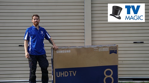 Technician standing next to a large TV box