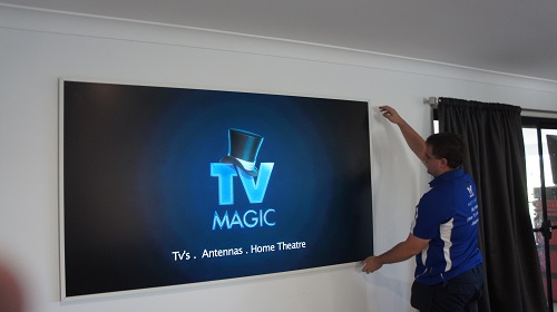 Technician hanging a large TV on the wall. Logo on screen