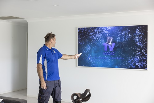 Technician in front of a large TV he just installed.