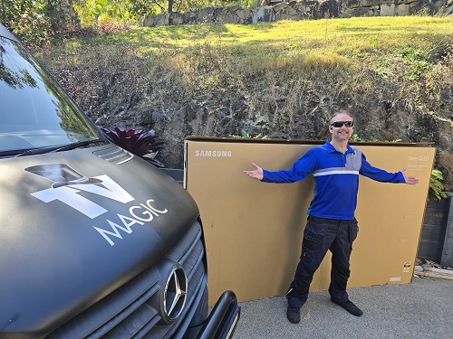 Technician standing with a massive TV, ready to transport
